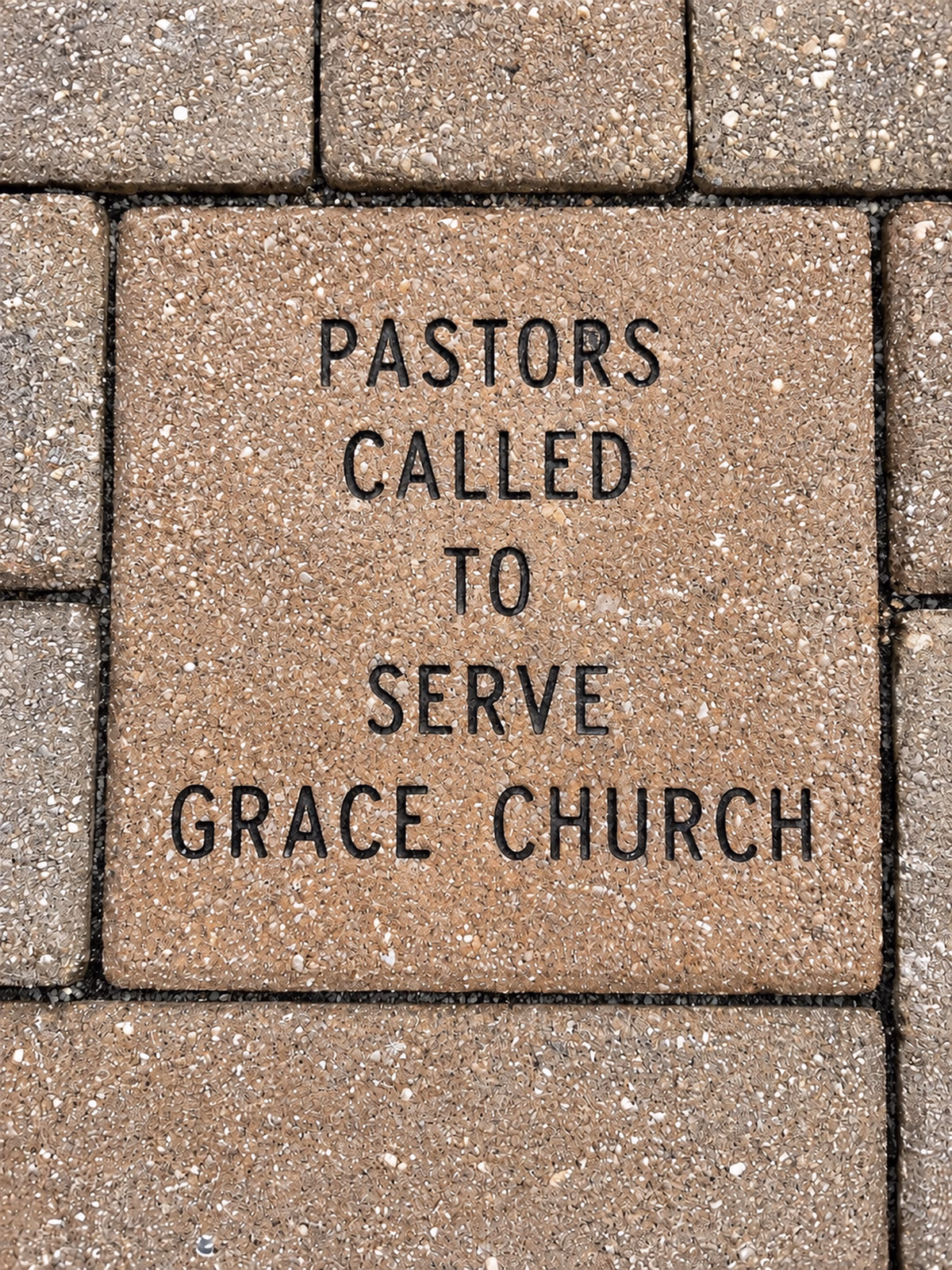 A close view of an engraved paver in the Celebration Walk, inscribed “Pastors Called to Serve Grace Church,” set among the surrounding brick pathway.