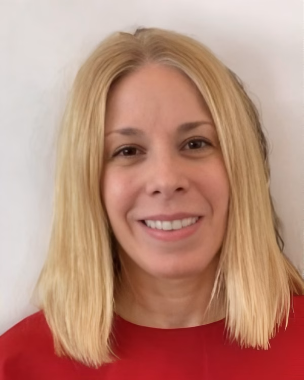 Carol Gallo, smiling, with shoulder-length blonde hair and a red top.